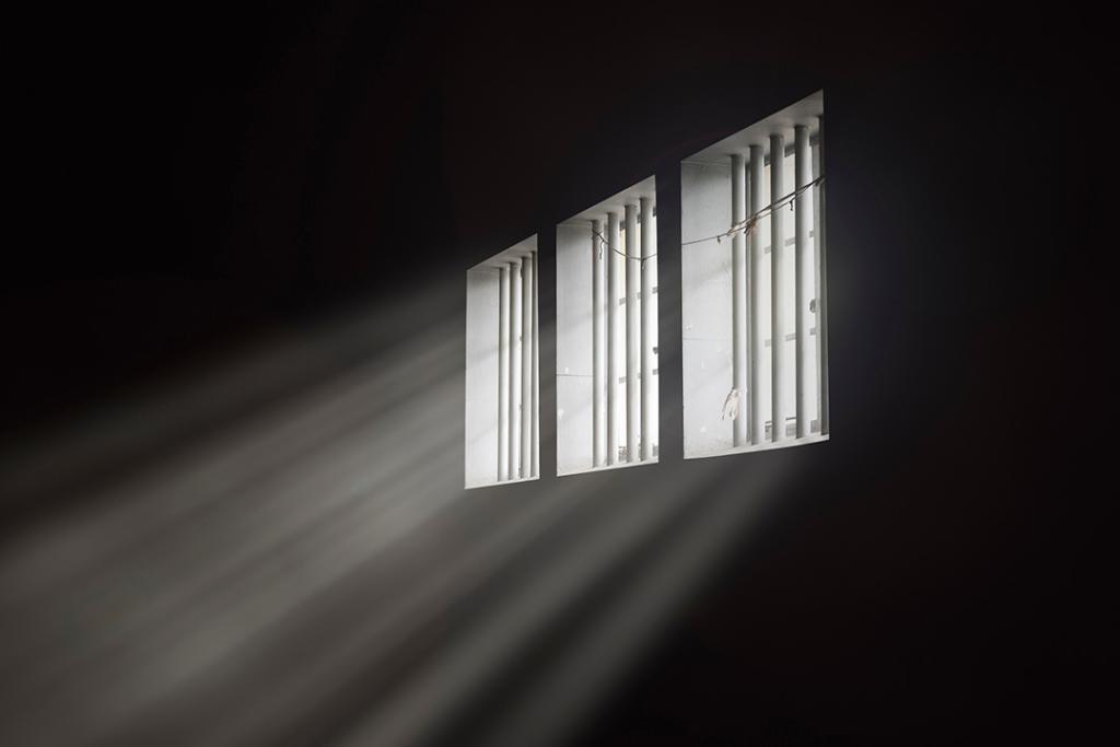 Beams of light through a barred prison cell window.