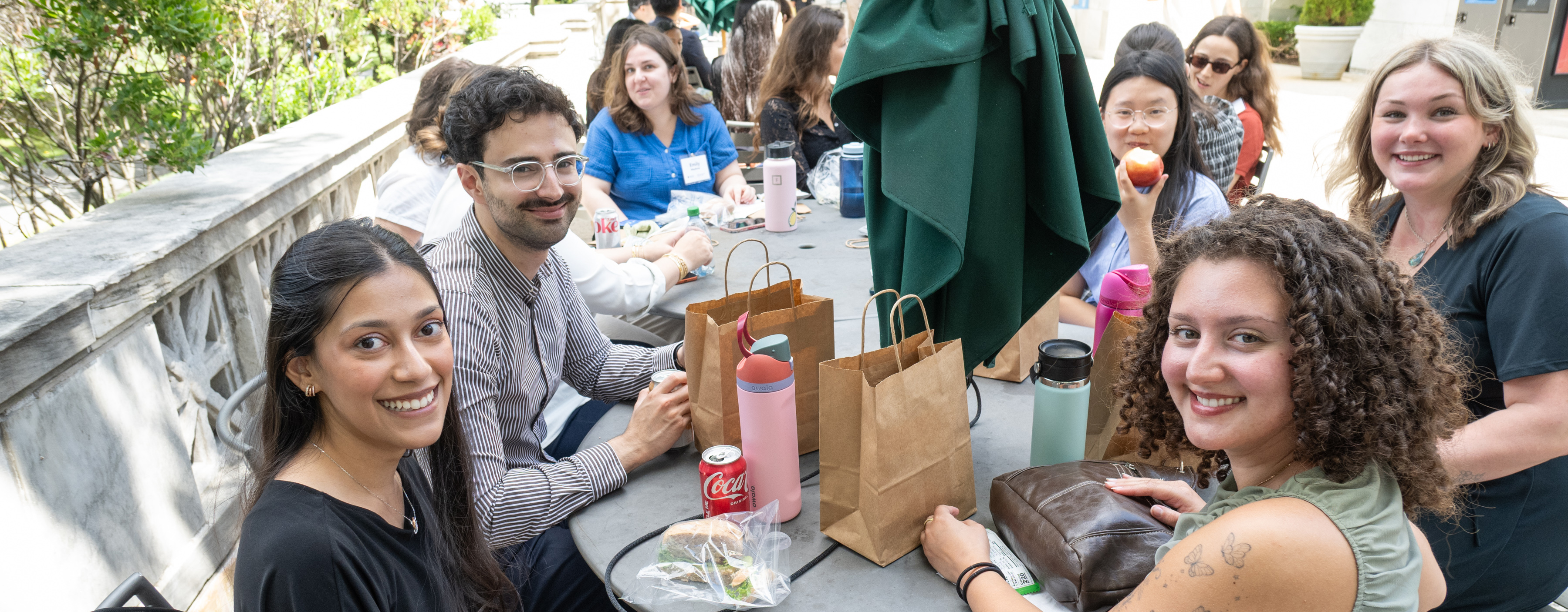 Students seated at tables outside, eating lunch together.
