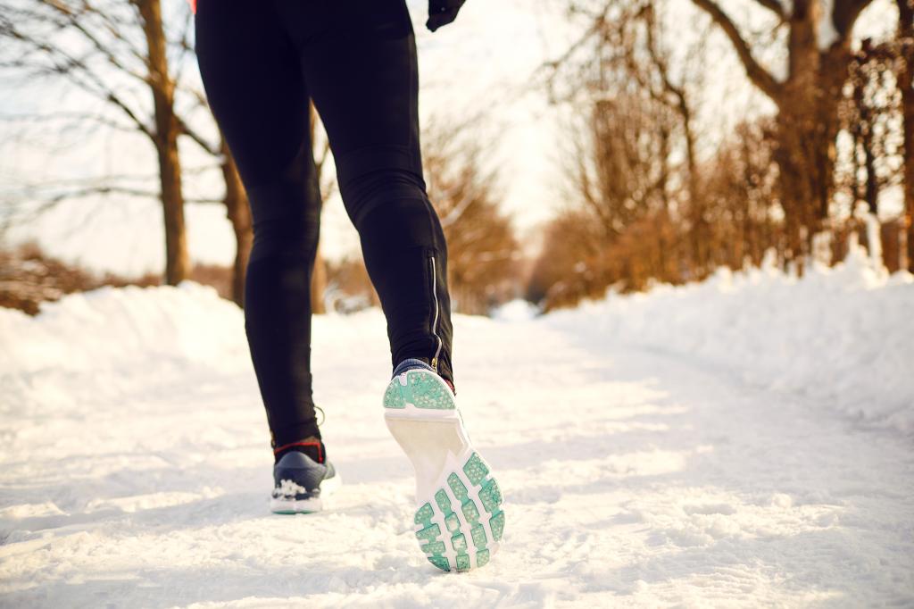 Closeup of sneakers on a person jogging in a snowy landscape
