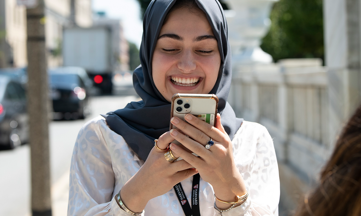 MBE student smiling at their smartphone.