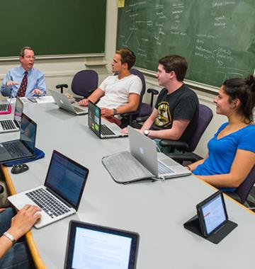 Ed Hundert and students with laptops sitting around a conference table.