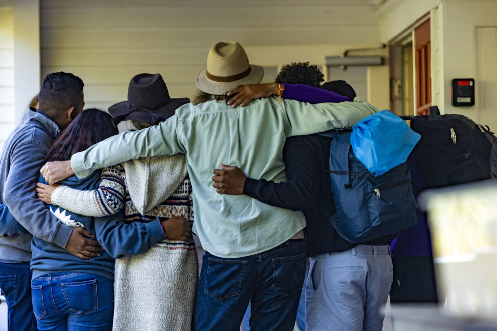 Immigrants and volunteers are arm-in-arm in a huddle leaving St. Andrews Parish House in Edgartown