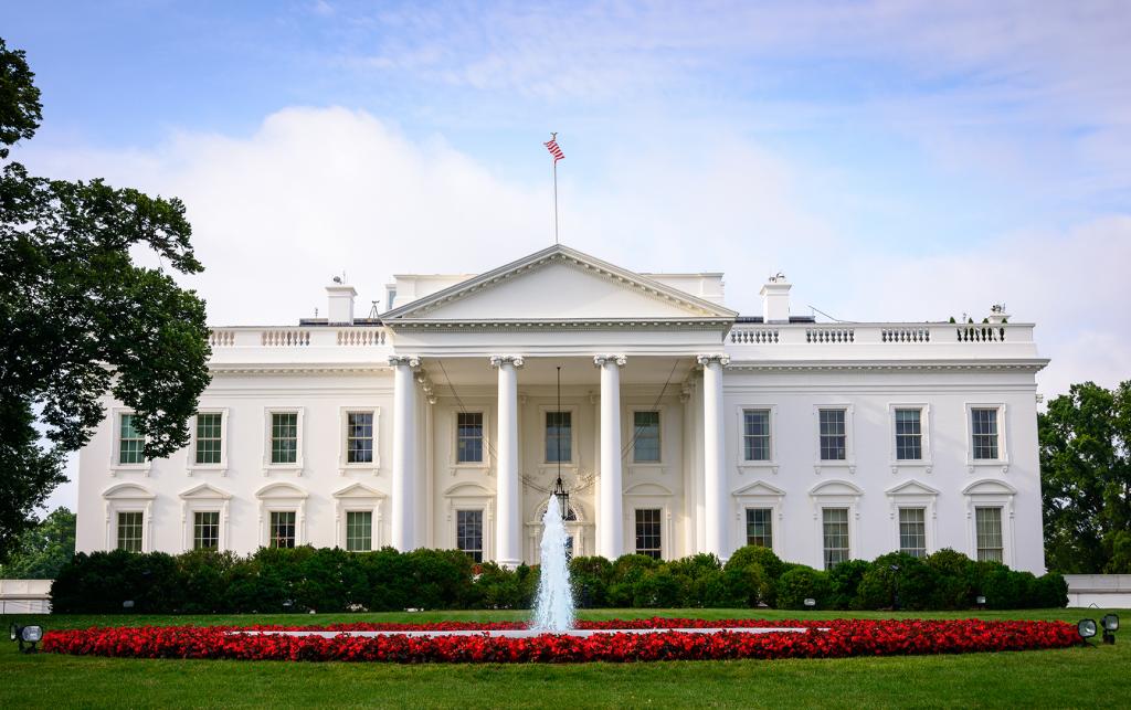 The White House with red flowers around the fountain on the front lawn